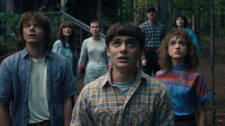 El elenco de "Stranger Things" se para uno al lado del otro y mira hacia arriba.
