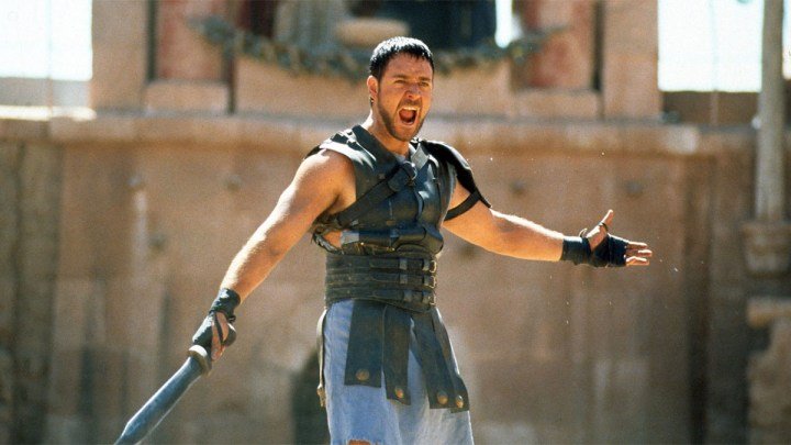 Russell Crowe extiende sus manos en la arena para Gladiator.
