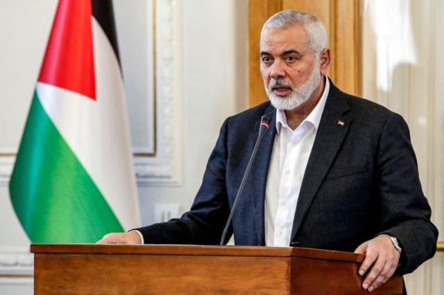 Ismail Haniya, habla tras un atril flanqueado por una bandera palestina. 