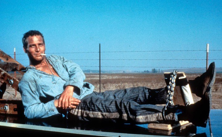 Un preso se sienta en un coche mientras fuma un cigarrillo.