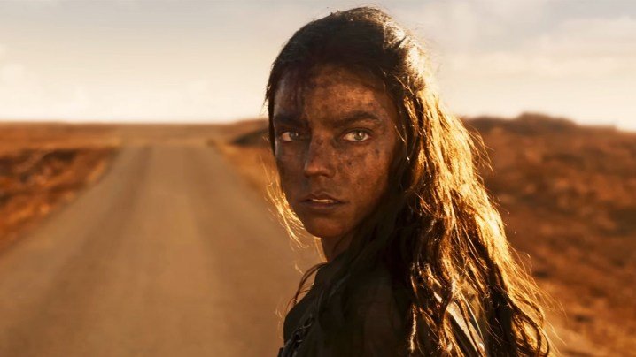 Anya Taylor-Joy está de pie en un camino polvoriento y mira por encima del hombro en un fotograma de Furiosa: Una saga de Mad Max.