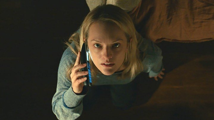 Elisabeth Moss mirando hacia arriba en una vista aérea mientras habla por teléfono en una escena de El hombre invisible.