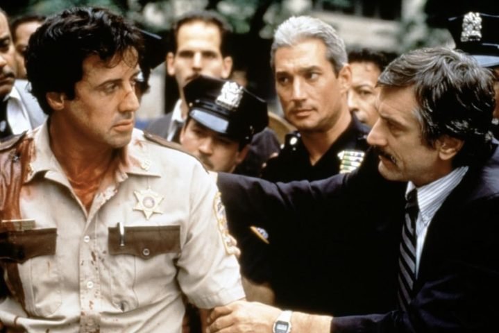 Un oficial de policía ensangrentado es retenido por un investigador.