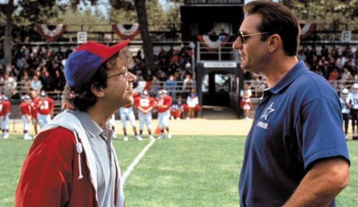 Dos entrenadores de fútbol se paran uno frente al otro en un campo de fútbol.