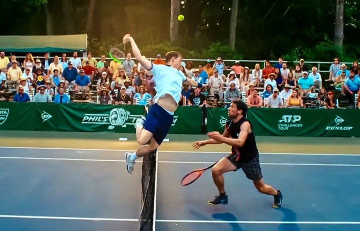 Un hombre salta sobre la red de una cancha de tenis en Challengers.