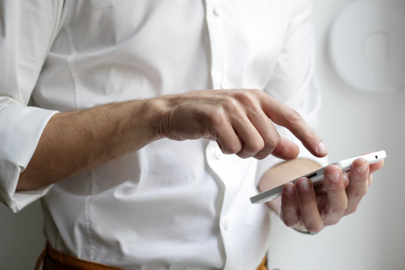 Una persona sostiene un teléfono mientras presiona su pantalla