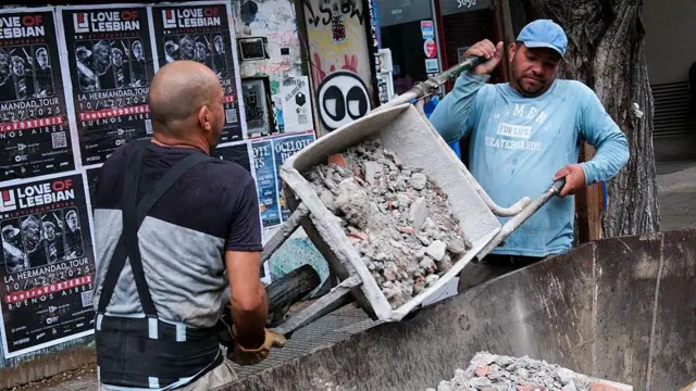 Trabajadores de la construcción vacían una carretilla en un contenedor el 24 de octubre de 2025, Buenos Aires, Argentina.