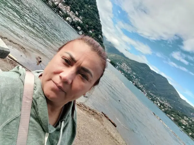 Yulixa con un saco verde al lado de un lago