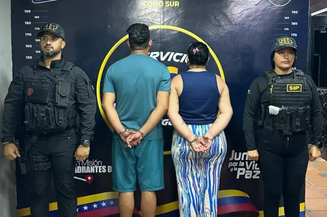 Dos personas de espalda, esposadas, con policías a los lados